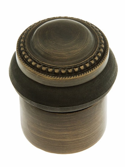 Beaded Edge Floor Mount Door Stop in Antique Brass.